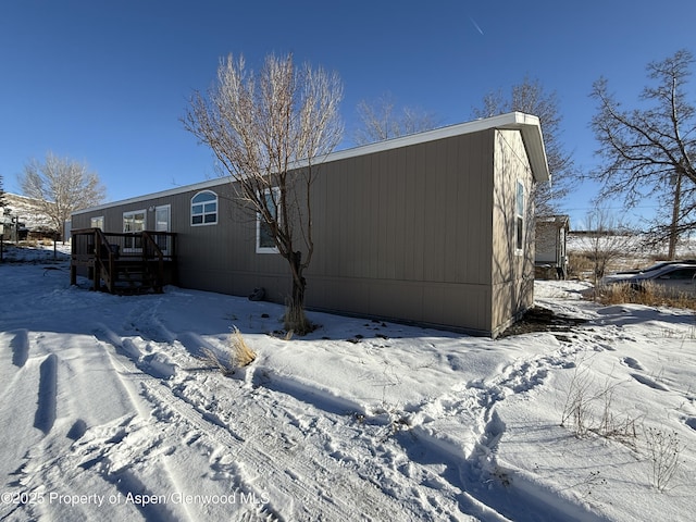 snow covered back of property featuring a wooden deck