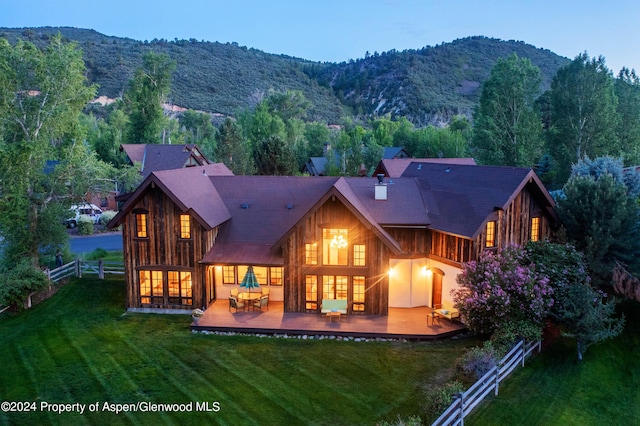 rear view of property with a lawn and a deck with mountain view