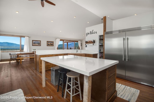 kitchen with a mountain view, built in refrigerator, dark hardwood / wood-style floors, ceiling fan, and a kitchen island