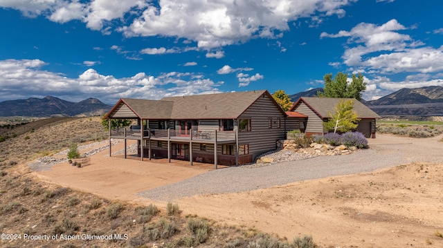 back of property with a deck with mountain view