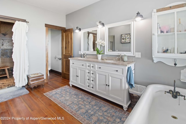 bathroom featuring a tub to relax in, vanity, wood-type flooring, and toilet