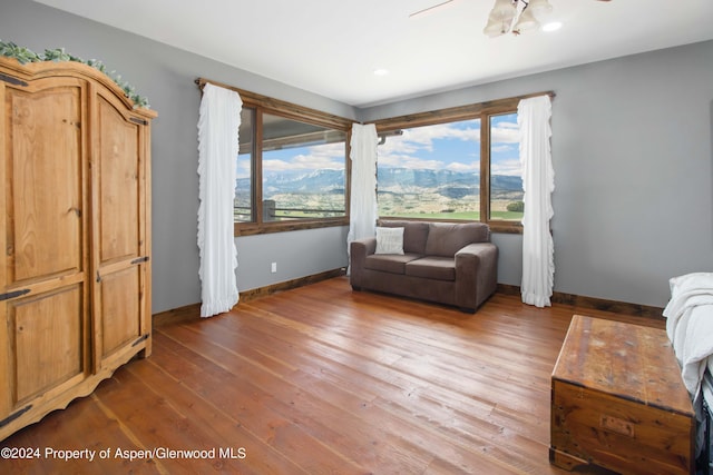 living room with a mountain view, wood-type flooring, and ceiling fan