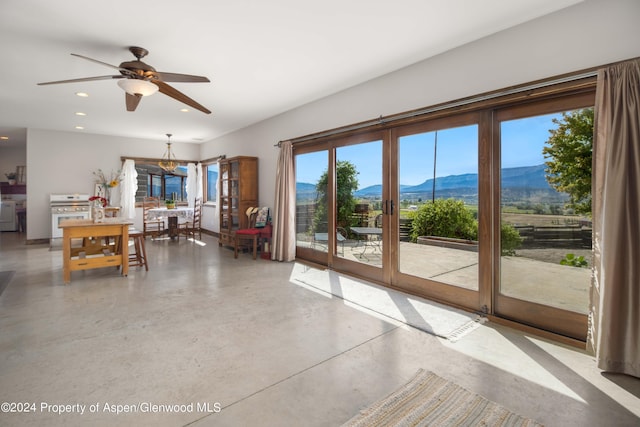 unfurnished living room with a mountain view, french doors, ceiling fan, and a healthy amount of sunlight