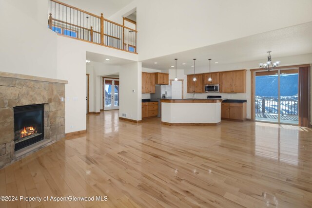 unfurnished living room with a fireplace, light wood-type flooring, a chandelier, and a healthy amount of sunlight