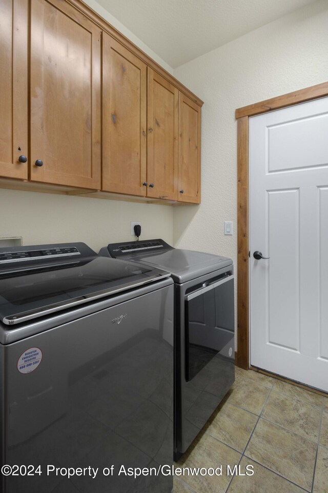 clothes washing area featuring separate washer and dryer and cabinets