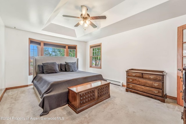 carpeted bedroom featuring baseboard heating, a raised ceiling, and ceiling fan