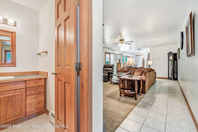 hall with sink, light colored carpet, and a baseboard radiator