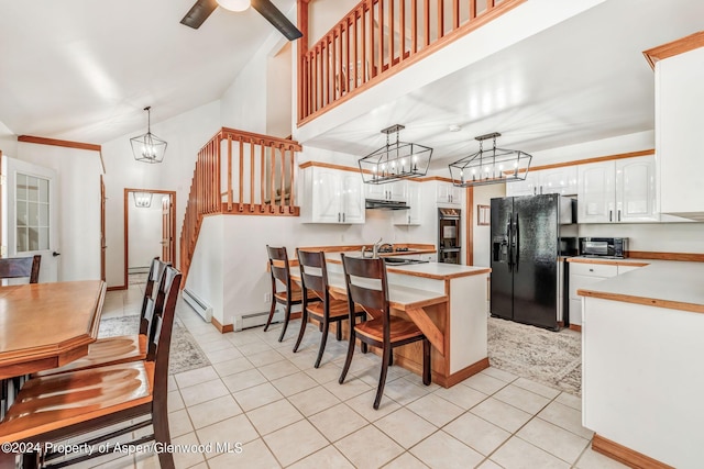 kitchen with white cabinets, black fridge with ice dispenser, baseboard heating, and hanging light fixtures