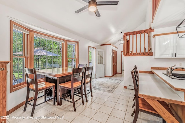 tiled dining room featuring baseboard heating, ceiling fan, sink, and lofted ceiling