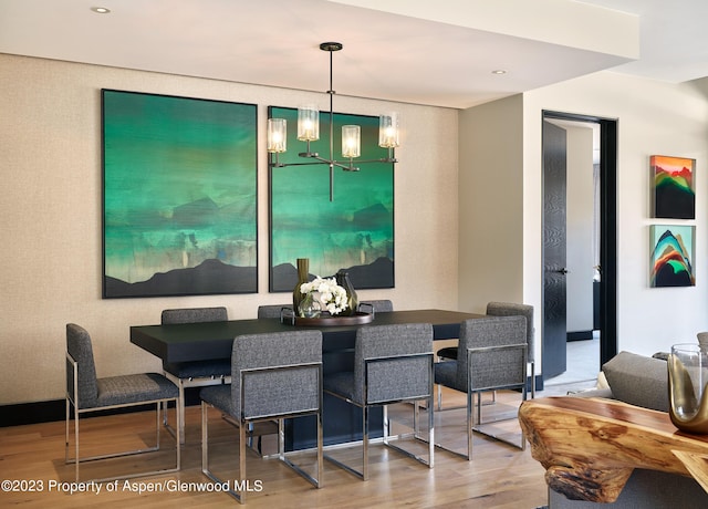 dining area with hardwood / wood-style floors and an inviting chandelier