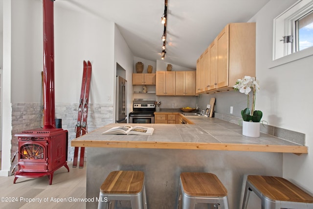 kitchen with a sink, light brown cabinets, rail lighting, stainless steel appliances, and tile countertops