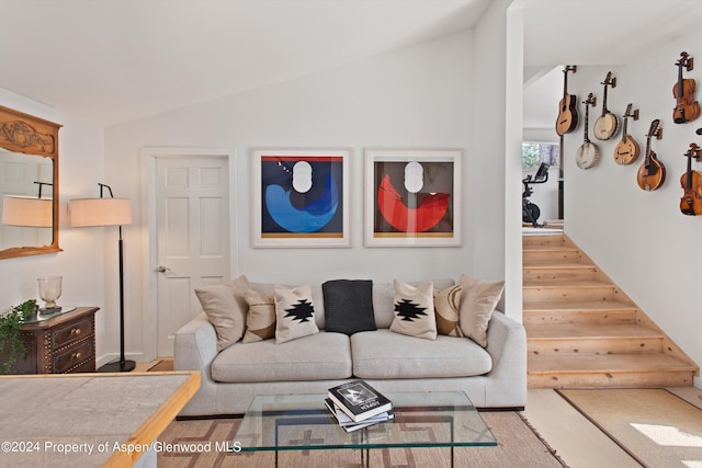 living room featuring stairs, wood finished floors, and vaulted ceiling