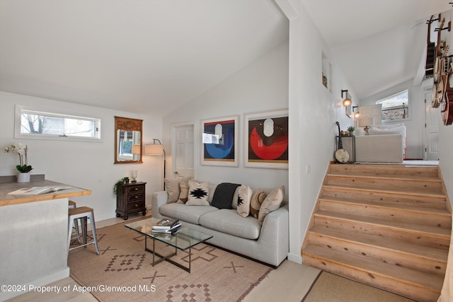 living room featuring baseboards, stairs, and lofted ceiling