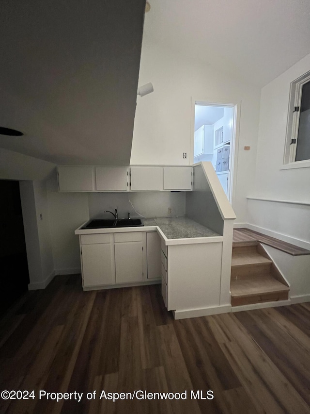 kitchen featuring light countertops, dark wood finished floors, white cabinetry, baseboards, and vaulted ceiling