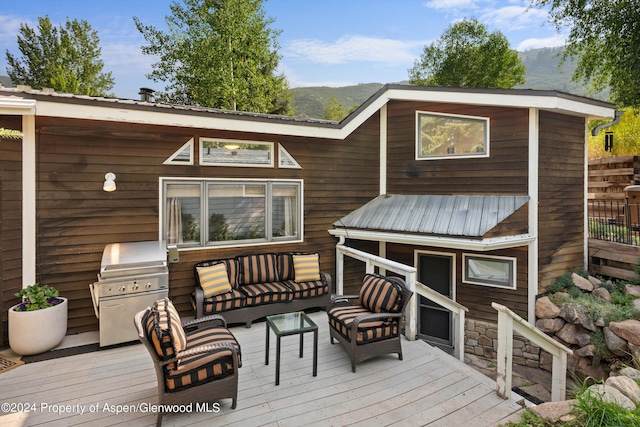 deck with outdoor lounge area, a mountain view, and grilling area