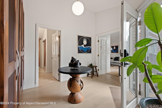 hall featuring baseboards, french doors, and light wood-style flooring