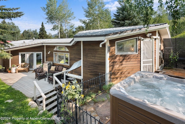 back of house featuring a hot tub, fence, a deck, and metal roof