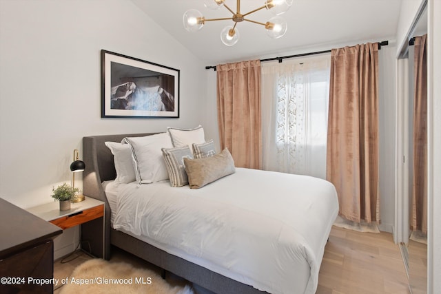 bedroom featuring lofted ceiling, light wood-style flooring, and a chandelier