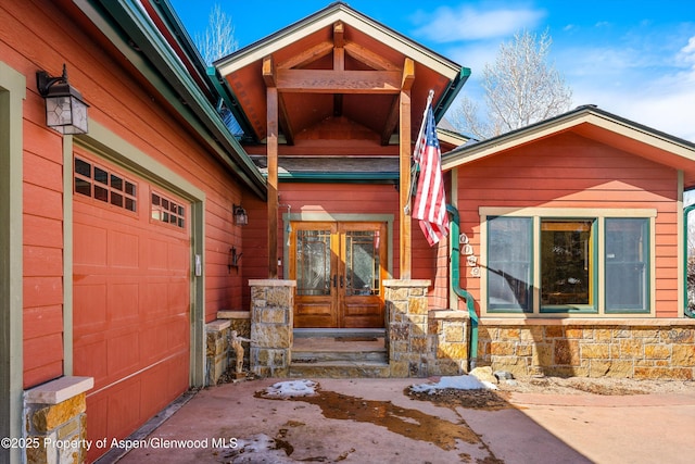 property entrance with a garage, stone siding, and french doors