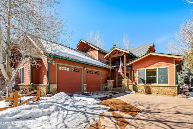 view of front of house featuring a garage, stone siding, fence, and concrete driveway