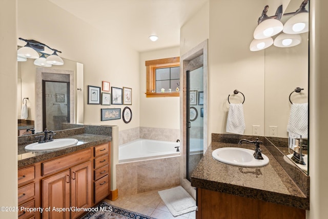 full bath featuring a bath, tile patterned flooring, two vanities, and a sink