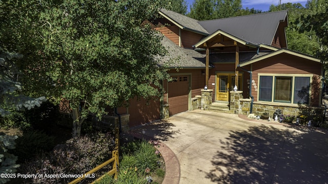 view of front of property featuring a garage, stone siding, and concrete driveway