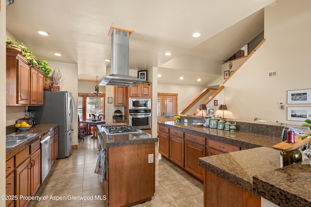 kitchen featuring visible vents, island range hood, brown cabinets, and a center island