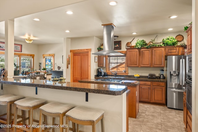 kitchen featuring appliances with stainless steel finishes, recessed lighting, island exhaust hood, and a kitchen breakfast bar