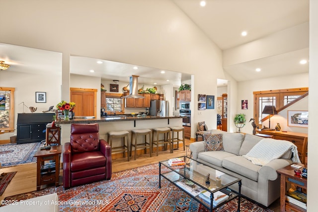 living area featuring high vaulted ceiling, light wood-type flooring, and recessed lighting