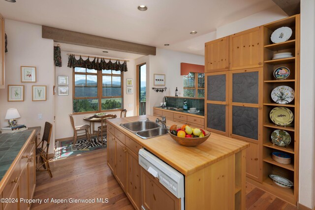 kitchen featuring a center island with sink, white dishwasher, sink, tile counters, and wood-type flooring