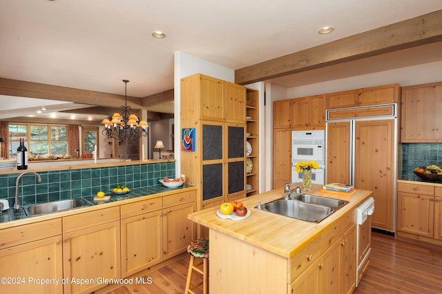 kitchen featuring a kitchen island with sink, sink, pendant lighting, an inviting chandelier, and beamed ceiling