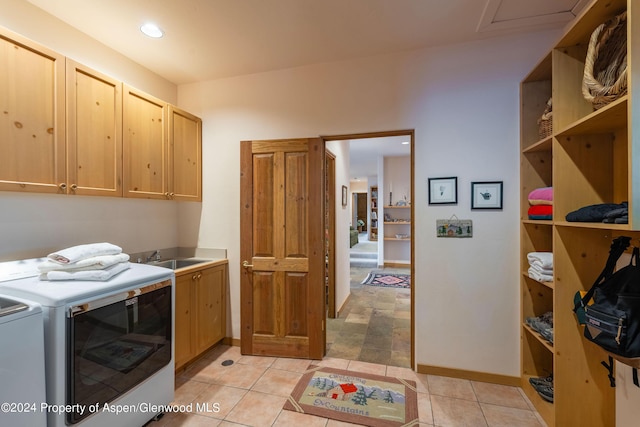 laundry area with light tile patterned flooring, cabinets, separate washer and dryer, and sink