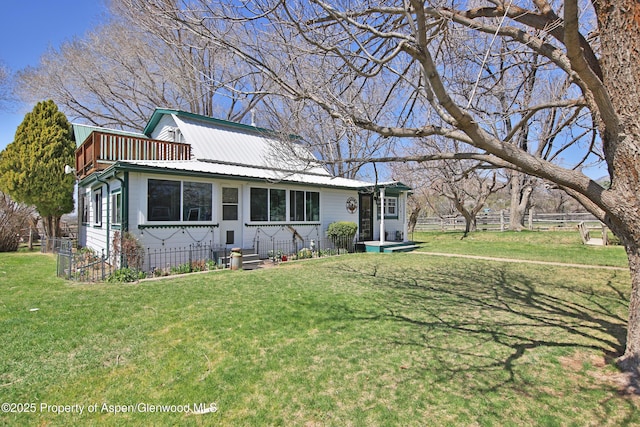 bungalow-style house with a front yard, fence, and metal roof