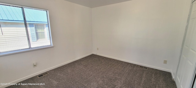 unfurnished room featuring baseboards, visible vents, and dark colored carpet