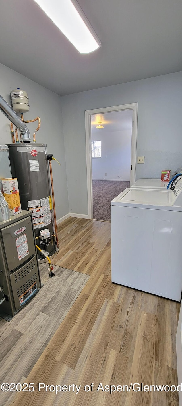 laundry area featuring wood finished floors, baseboards, washing machine and clothes dryer, laundry area, and water heater