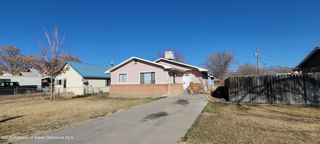 view of front of property with a front yard, fence, brick siding, and stucco siding