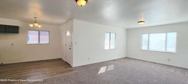 foyer entrance featuring carpet flooring, baseboards, and a chandelier