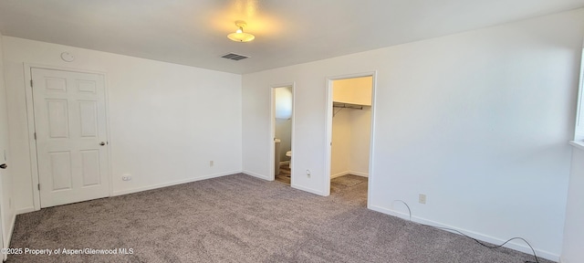 unfurnished bedroom with visible vents, carpet flooring, a walk in closet, and baseboards