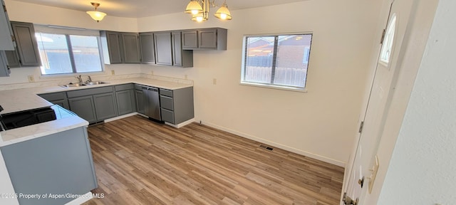 kitchen with gray cabinets, dishwasher, light wood-style floors, and a sink