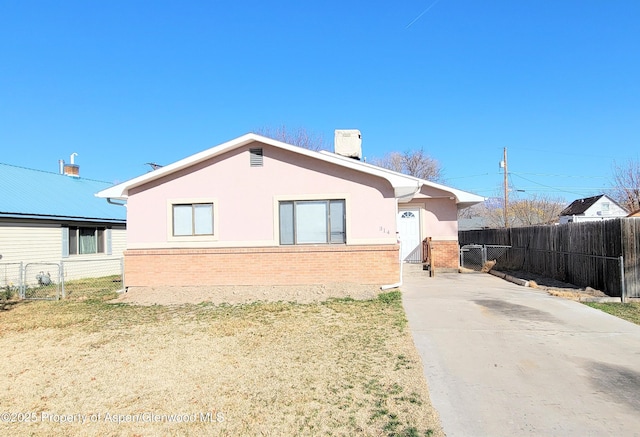 view of front of house featuring a chimney, fence, brick siding, and stucco siding