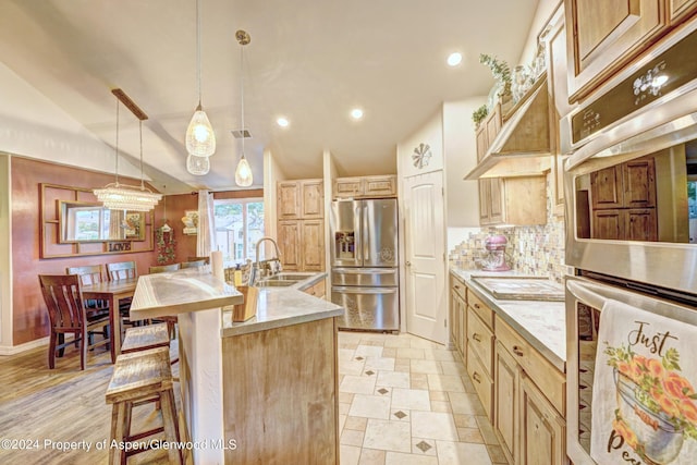 kitchen featuring stainless steel appliances, sink, pendant lighting, lofted ceiling, and an island with sink