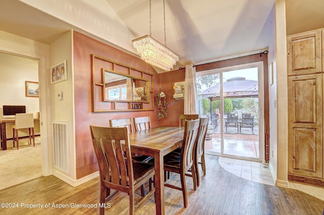 dining room with hardwood / wood-style flooring, lofted ceiling, and an inviting chandelier