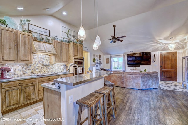 kitchen with a kitchen breakfast bar, backsplash, pendant lighting, custom range hood, and electric stovetop