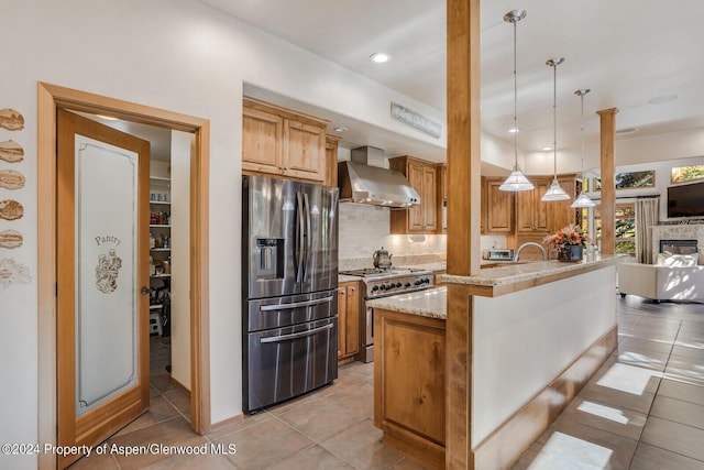 kitchen with backsplash, wall chimney exhaust hood, stainless steel appliances, a center island with sink, and hanging light fixtures