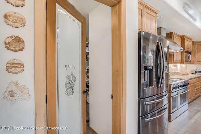 kitchen with light brown cabinets, backsplash, stainless steel appliances, and light tile patterned flooring