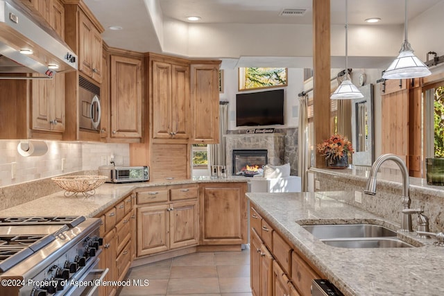 kitchen featuring pendant lighting, light stone counters, sink, and extractor fan