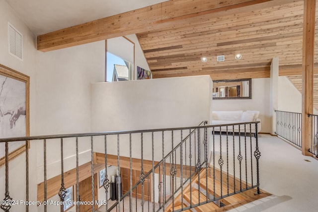 hallway with vaulted ceiling with beams, light colored carpet, and wooden ceiling