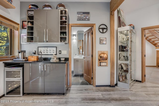 kitchen with sink, beverage cooler, and light wood-type flooring