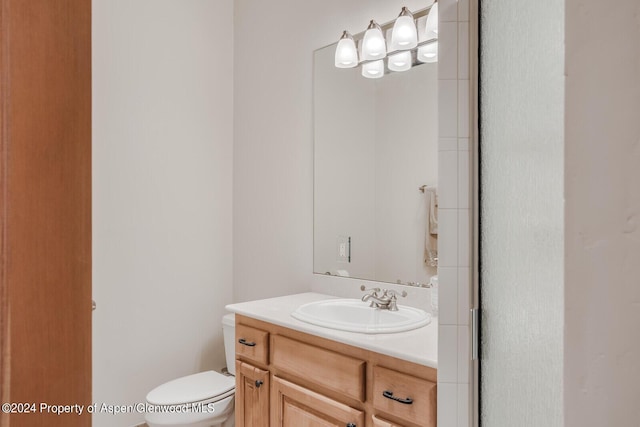 bathroom featuring vanity, toilet, and a shower with shower door