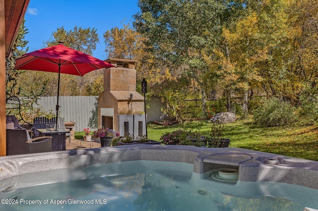 view of swimming pool with a patio area, a yard, a hot tub, and an outdoor fireplace